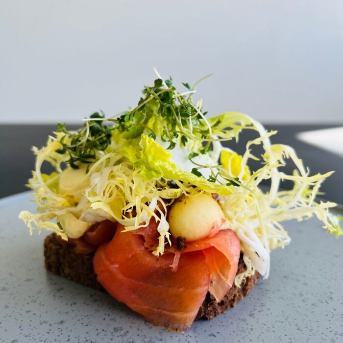 Smørrebrød med koldrøget laks, radiser, sennepscreme, radiser, æbler og krydderurter